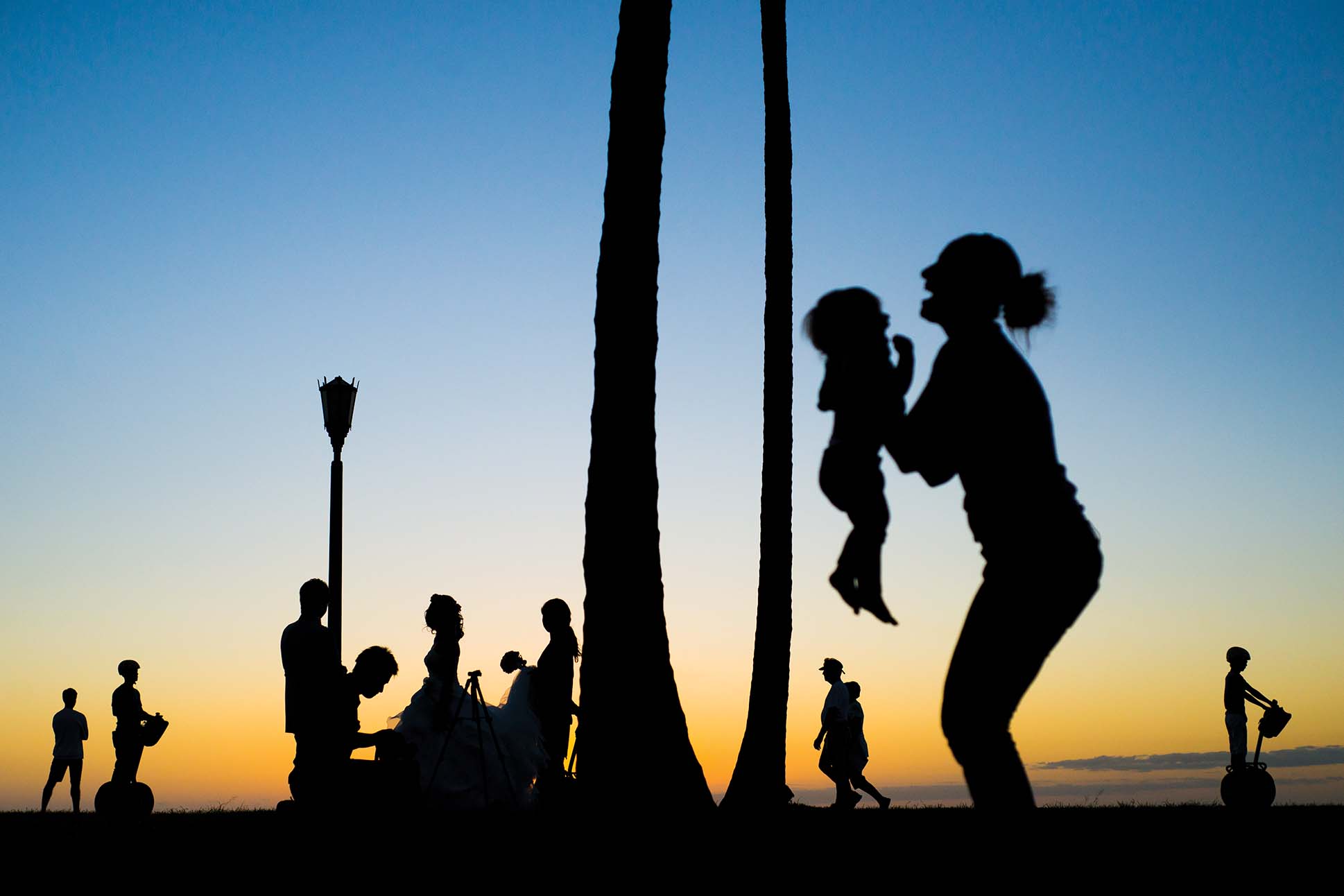 street photo of silhouettes of people on the beach in Honolulu against a sunset