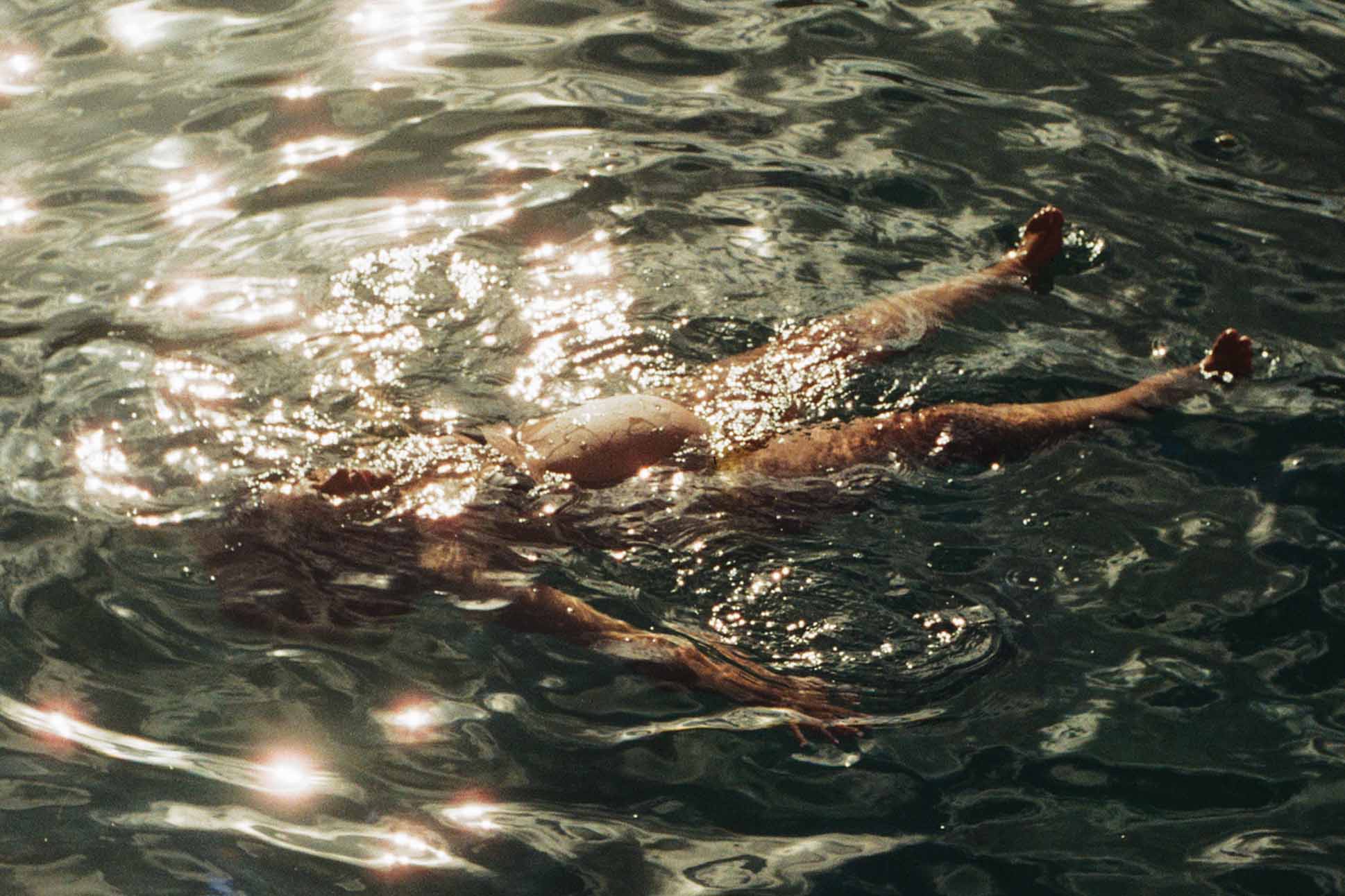 a person swimming in water, a photo by Nani Welch Keli‘iho‘omalu