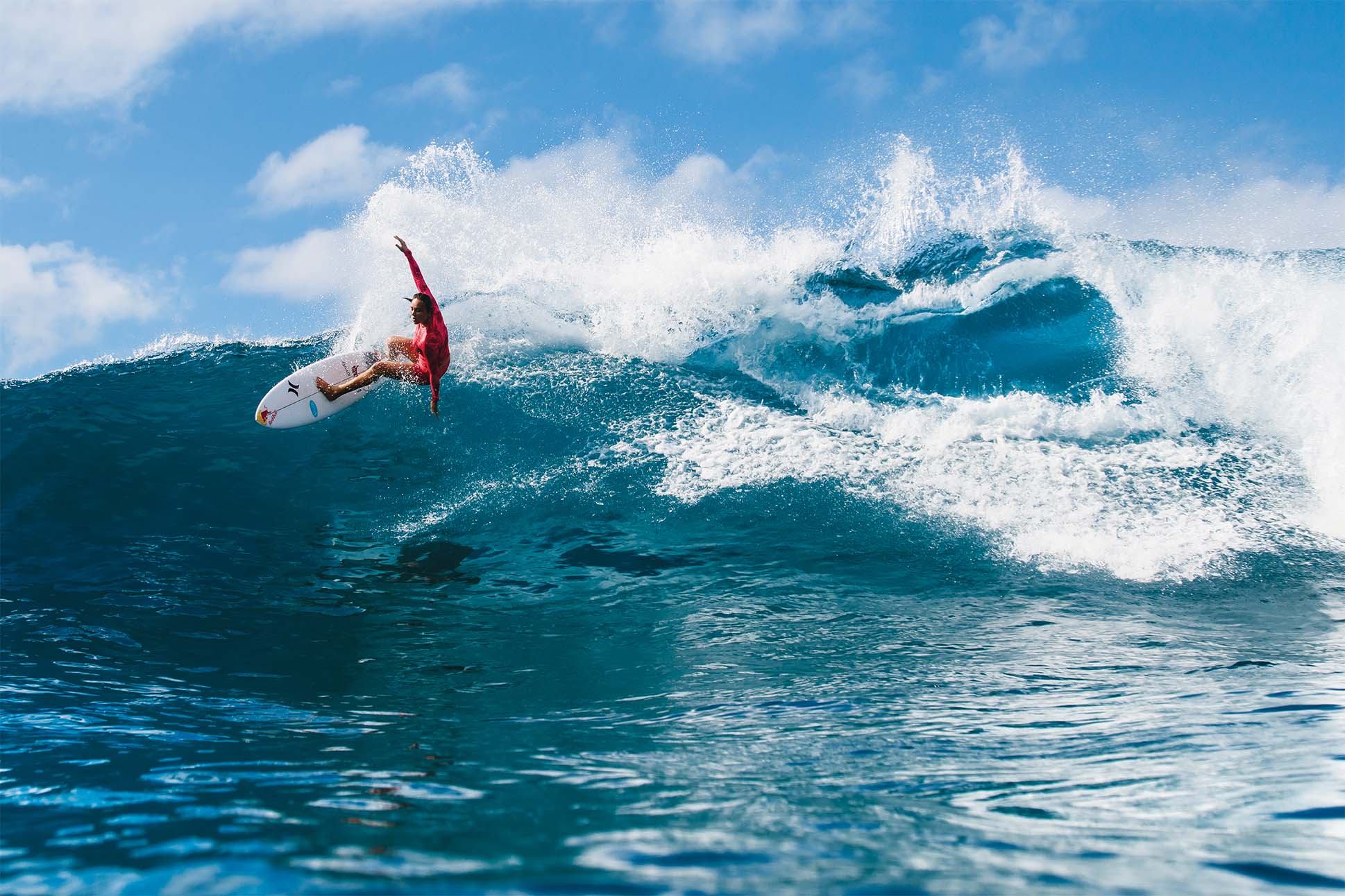 female surfer on a wave in a bright pink surf suit