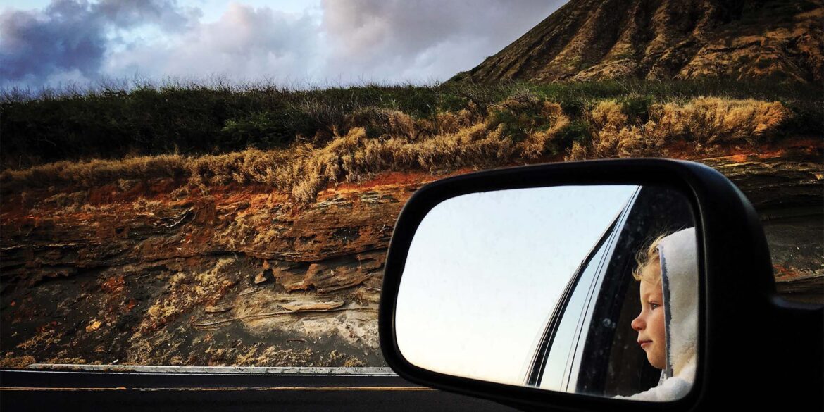 a side view mirror of a child looking out of a car window
