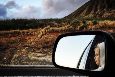 a side view mirror of a child looking out of a car window