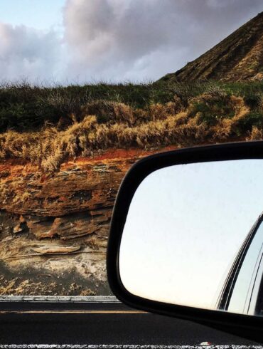 a side view mirror of a child looking out of a car window