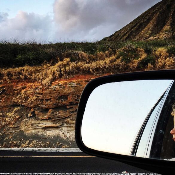 a side view mirror of a child looking out of a car window