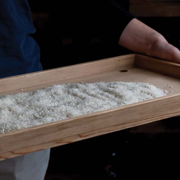 a person holding a wooden tray with white crystals