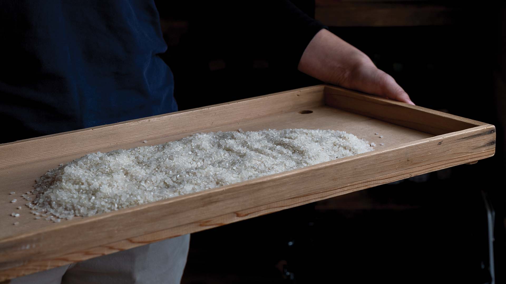 a person holding a wooden tray with white crystals